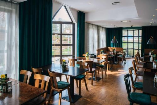 a restaurant with tables and chairs and windows at Vienna House Easy by Wyndham Castrop-Rauxel in Castrop-Rauxel