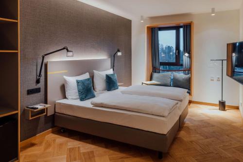 a bedroom with a large bed with blue pillows at Vienna House by Wyndham MQ Kronberg in Kronberg im Taunus