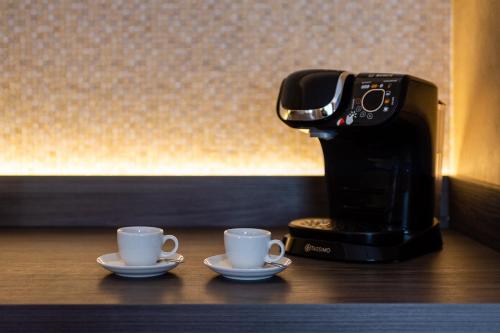 two coffee cups on a counter next to a coffee maker at Parkhotel Görlitz in Görlitz