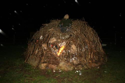 a man sitting on top of a pile of fire at Malomdűlő Farmház in Pilisborosjenő