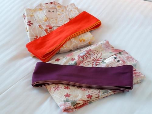 three different colored bags sitting on a bed at Hotel Palm Spring in Iwaki