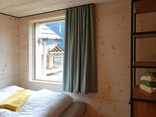 ein Schlafzimmer mit einem Fenster in einem Blockhaus in der Unterkunft Ferienhäuser Stiva Pintga 
