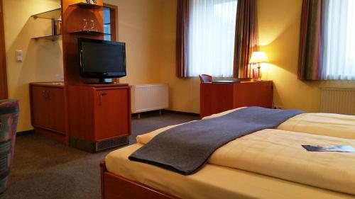 a hotel room with a bed and a flat screen tv at City Partner Hotel Strauss in Würzburg