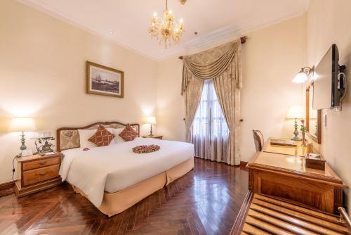 a bedroom with a large white bed and a window at Hotel Grand Saigon in Ho Chi Minh City
