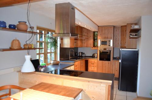 uma cozinha com armários de madeira e um frigorífico preto em Holmgård em Süderholm