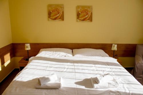 a large white bed with two towels on it at Penzion Bojnice in Bojnice