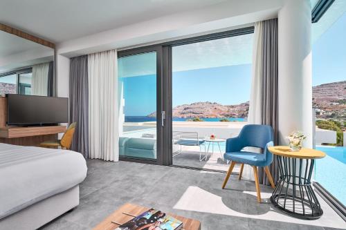 a hotel room with a bed and a view of a pool at Lindos Grand Resort & Spa - Adults Only in Líndos