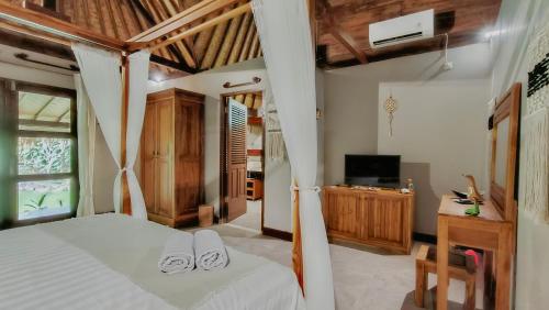 a bedroom with a bed with white sheets and a television at Dalai Tropical in Kuta Lombok