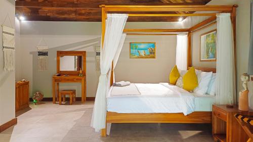 a bedroom with a wooden canopy bed with yellow pillows at Dalai Tropical in Kuta Lombok