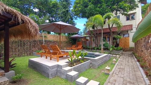 a patio with chairs and an umbrella in a yard at Dalai Tropical in Kuta Lombok