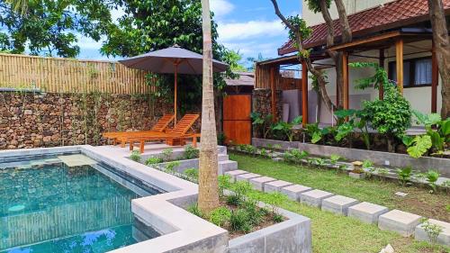 a house with a pool and a table and an umbrella at Dalai Tropical in Kuta Lombok