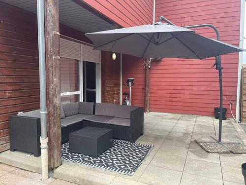 une terrasse avec un canapé et un parasol dans l'établissement Maison entière Chenôve avec jardin, à Chenôve