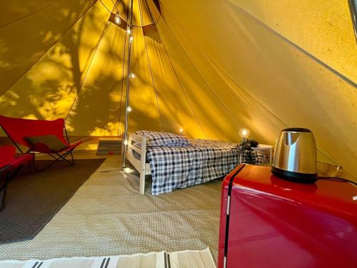 a tent with a bed and a chair in a room at Tente Indiana Pins - La Téouleyre in Saint-Julien-en-Born
