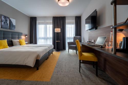 レーゲンスブルクにあるHotel INCLUDiOのベッド、デスク、ノートパソコンが備わるホテルルームです。