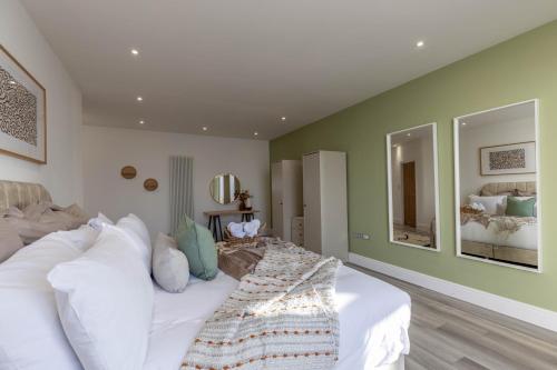 a bedroom with a large white bed and two mirrors at Luxury 1BR Seafront Apartment in Cardiff