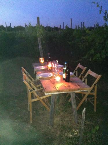a wooden table with candles and wine bottles on it at Cascina La Maddalena Bed & Wine in Rocca Grimalda