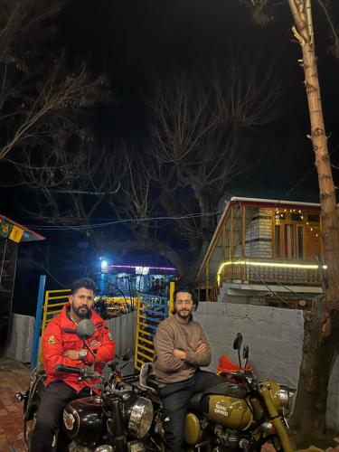 two men sitting on a motorcycle at night at Nirvana by Oztel - Backpacker Hostel in Kasol