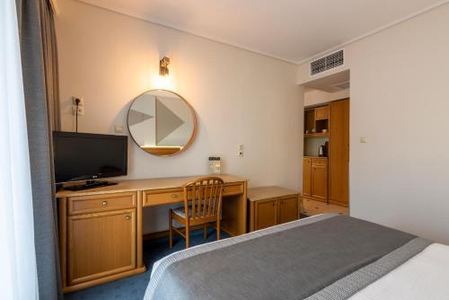 a bedroom with a bed and a desk with a television at Poseidonio in Piraeus