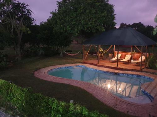 a swimming pool with a gazebo in a yard at Milkwood Country House in Port Elizabeth