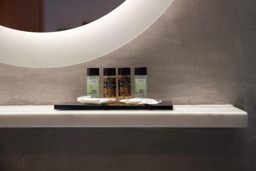 a shelf with four products on it under a mirror at Poseidonio in Piraeus