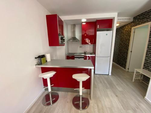cocina con armarios rojos y nevera blanca en Apartamento Cuzco, en Madrid