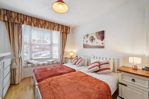 Comfortable 2 bedroom property, Maidstone في ميدستون: غرفة نوم بسريرين ونافذة