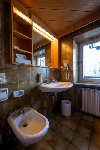 a bathroom with two sinks and a window at Sporthotel Teresa in Badia