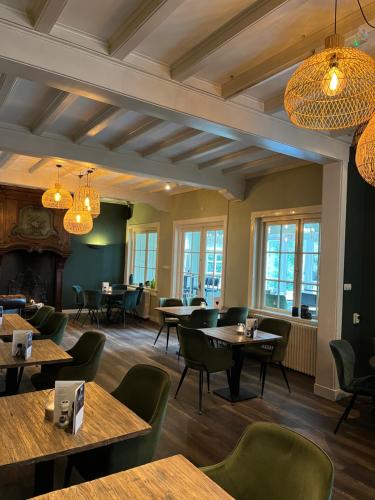 ダルフセンにあるHotel De Baronesのテーブルと椅子、シャンデリアのあるレストラン