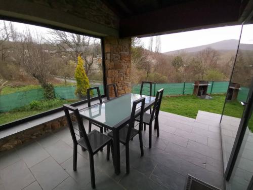 einen Tisch und Stühle auf einer abgeschirmten Veranda mit Aussicht in der Unterkunft Alojamientos Marel Sanabria in Villarino de Sanabria