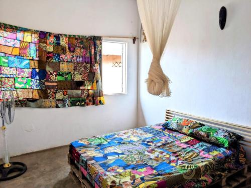 a bedroom with a bed with a colorful quilt on the wall at Chambres d'hôtes - Chez Mama Sêdjro in Porto-Novo