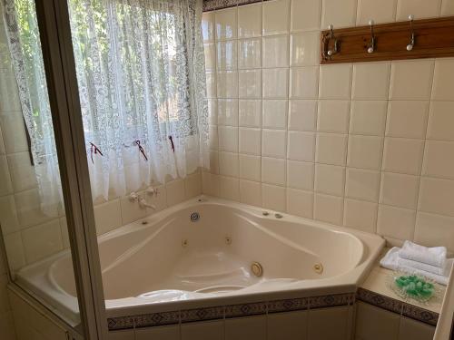 baño con bañera blanca y ventana en Foundry Cottages, en Rutherglen