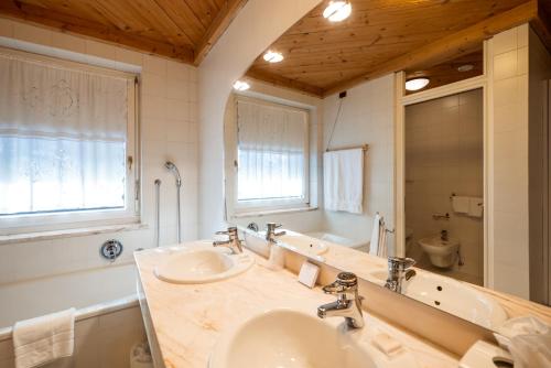 a bathroom with two sinks and a tub and a mirror at Sporthotel Teresa in Badia