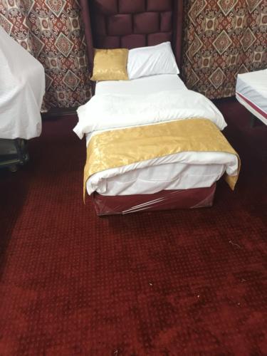 um quarto com 2 camas com lençóis brancos e dourados em غرف مجهزة سكن وتجارة عرعر رجال فقط em Arar