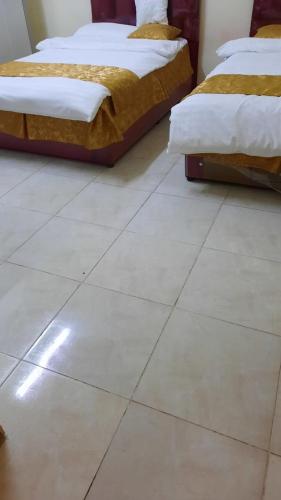 Duas camas sentadas em cima de um piso de azulejo branco em غرف مجهزة سكن وتجارة عرعر رجال فقط em Arar