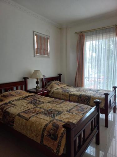 een slaapkamer met 2 bedden en een raam bij Margot Apartment Pondok Indah in Jakarta