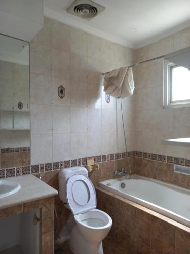 een badkamer met een toilet, een wastafel en een bad bij Margot Apartment Pondok Indah in Jakarta
