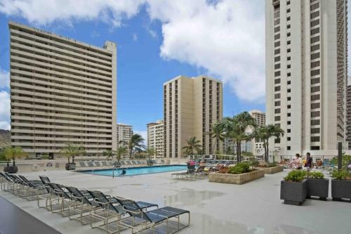 une piscine avec des chaises et des bâtiments en arrière-plan dans l'établissement Pe'a Ocean View Suite @Waikiki Banyan +1 Free Park, à Honolulu