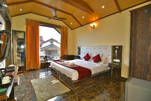 a bedroom with a large bed and a large window at Dalhousie valley Resort By DLS Hotels in Banikhet