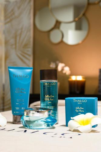 a table topped with two bottles of moisturizers and a candle at Hôtel & SPA Oceania L'Univers Tours in Tours