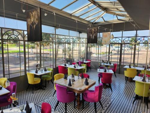 un restaurant avec des tables, des chaises et des fenêtres dans l'établissement Le Manoir d'à Côté, à Courseulles-sur-Mer