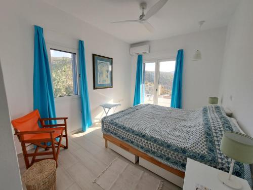 a bedroom with blue curtains and a bed and a chair at O Kipos in Zárakes