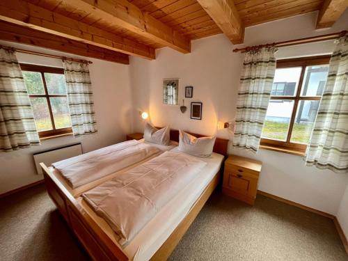 1 dormitorio con 1 cama grande y 2 ventanas en Waldhaus 46, 48, 49 im Waldferiendorf, en Regen