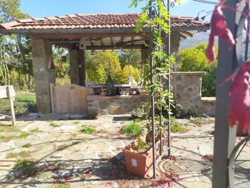 a stone pergola with a grill in a garden at b&b La Corte dei Cerri- Il Piccolo Chalet in Frassinoro