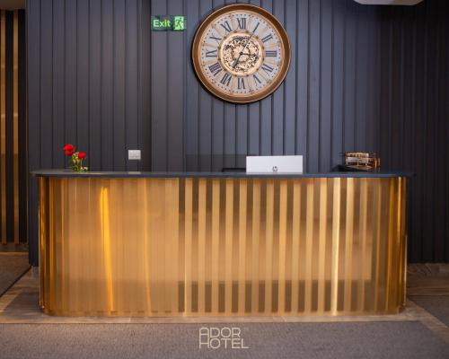 a large clock on the wall above a reception desk at Ador Hotel North Mitrovica in Mitrovicë