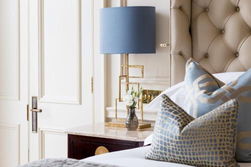 a bedroom with a bed with a blue lamp on a table at The Kensington Hotel in London