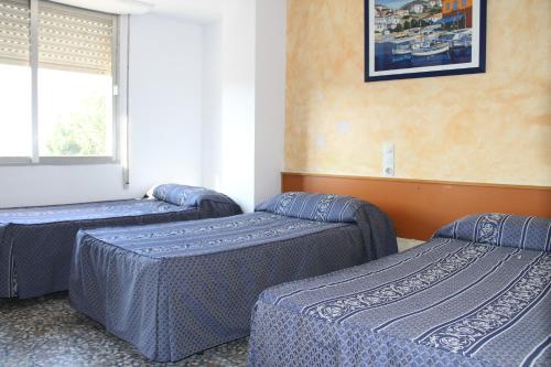 3 camas sentadas en una habitación con ventana en Hostal Mengual, en Gandía
