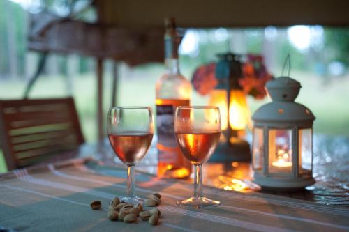 two glasses of wine and a lantern on a table at Tente Lodge Bouleau - La Téouleyre in Saint-Julien-en-Born