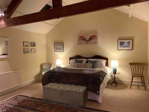a bedroom with a bed and two chairs and two lamps at The Old Granary at Red House Farm in Ripon