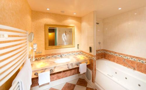 a bathroom with a tub and a sink at EurothermenResort Bad Hall - Hotel Miraverde in Bad Hall