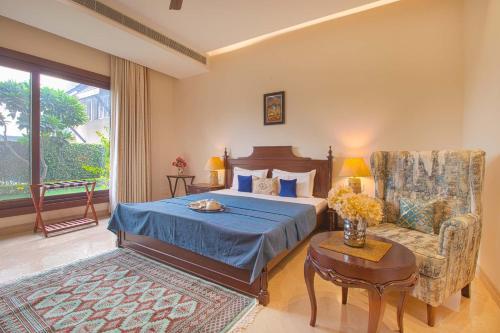 a bedroom with a bed and a chair and a table at Ekant Villa with Pvt Pool at Amritsar by StayVista in Amritsar